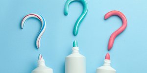 Trois tubes de dentifrice avec chacun du dentifrice en forme de point d'interrogation pour symboliser la question suivante : quels sont les avantages d'un dentifrice pour enfants  sans fluor ?